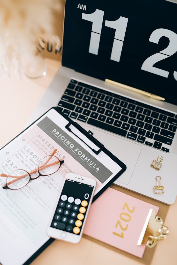 Overhead view of a laptop, smartphone, and planner on a clean workspace, emphasizing organization.